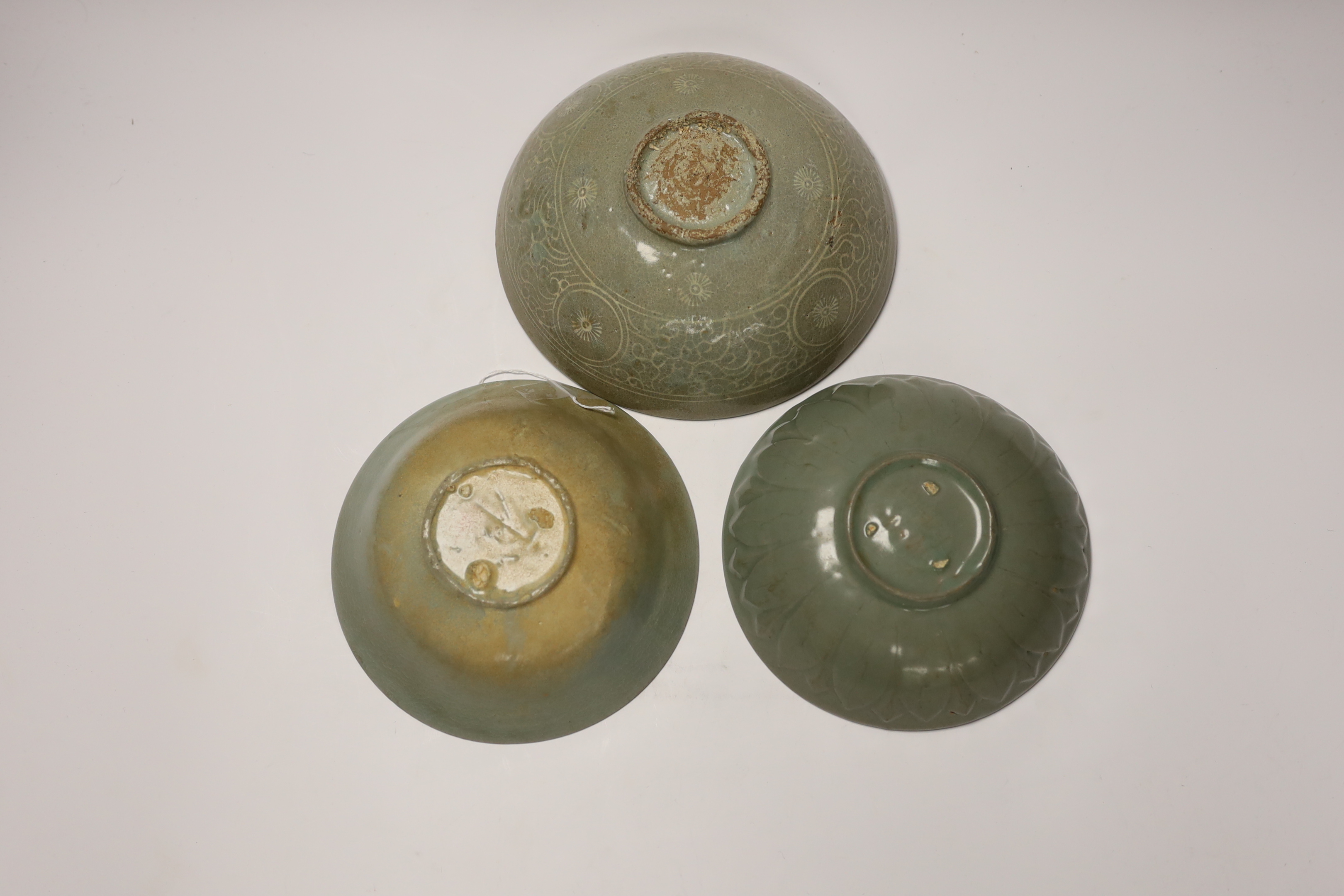 Two Korean celadon bowls, Goryeo dynasty (11th/12th century), the first carved with lotus petals to the underside, the second with fine crackle to the glaze, and a Korean slip-decorated celadon bowl (11th/12th century),